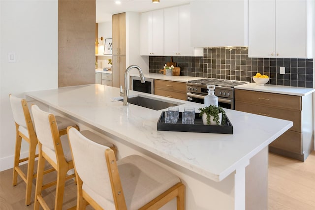 kitchen with white cabinets, a kitchen breakfast bar, light hardwood / wood-style flooring, high end stove, and kitchen peninsula