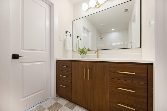 bathroom with a tile shower and vanity