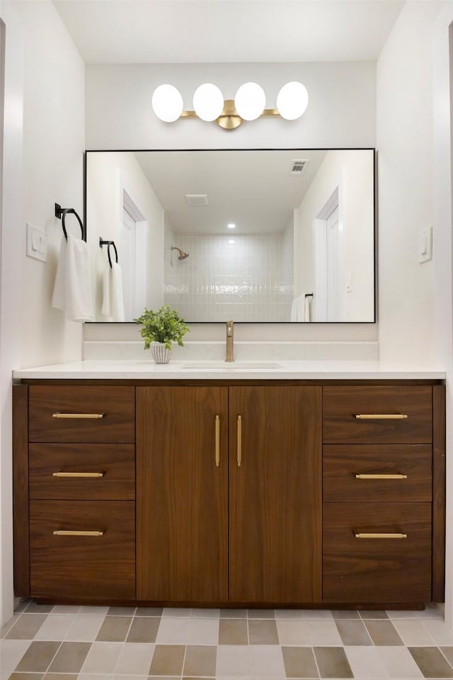 bathroom with a tile shower and vanity