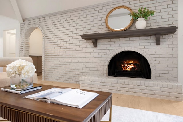 living room featuring light hardwood / wood-style flooring, brick wall, and a brick fireplace