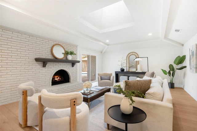 living room featuring lofted ceiling, light wood-type flooring, a fireplace, and brick wall