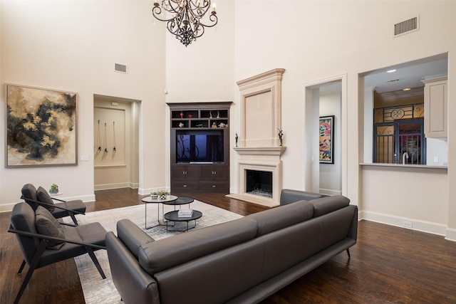 living room featuring dark hardwood / wood-style flooring, a towering ceiling, and an inviting chandelier