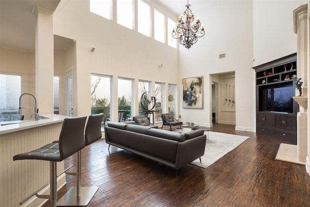 living room with dark hardwood / wood-style flooring, ornamental molding, a high ceiling, and a notable chandelier