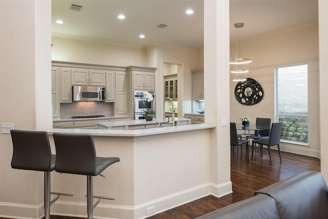 kitchen with a breakfast bar, dark wood-type flooring, crown molding, double wall oven, and kitchen peninsula