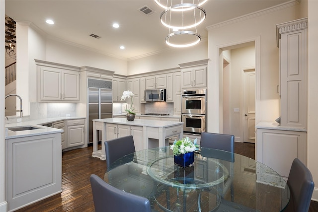 kitchen featuring pendant lighting, backsplash, sink, a kitchen island, and stainless steel appliances