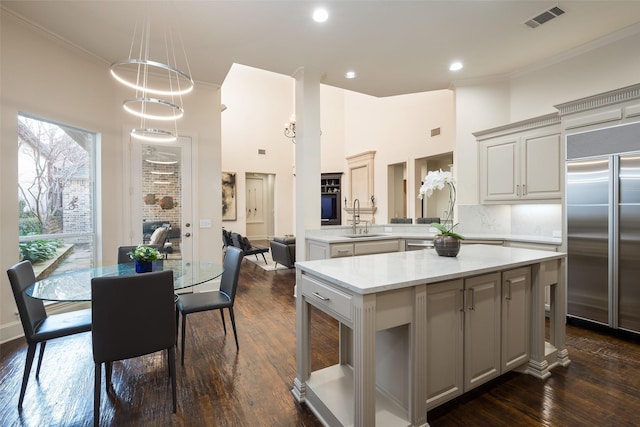 kitchen featuring kitchen peninsula, dark hardwood / wood-style flooring, stainless steel built in refrigerator, sink, and decorative light fixtures