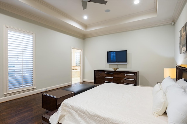 bedroom with ensuite bath, a tray ceiling, ceiling fan, dark wood-type flooring, and multiple windows