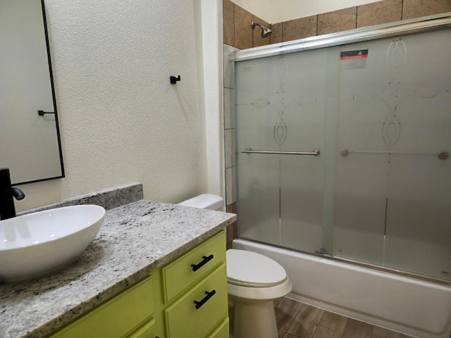 full bathroom with enclosed tub / shower combo, wood-type flooring, vanity, and toilet