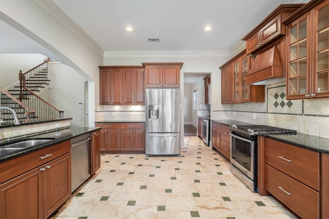 kitchen with sink, decorative backsplash, dark stone countertops, appliances with stainless steel finishes, and custom range hood