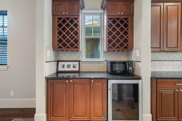 bar featuring dark hardwood / wood-style flooring, tasteful backsplash, beverage cooler, and dark stone countertops