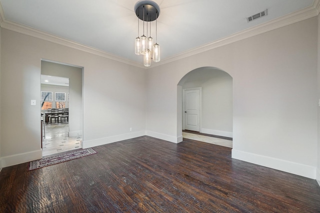 spare room featuring dark hardwood / wood-style flooring, crown molding, and a chandelier