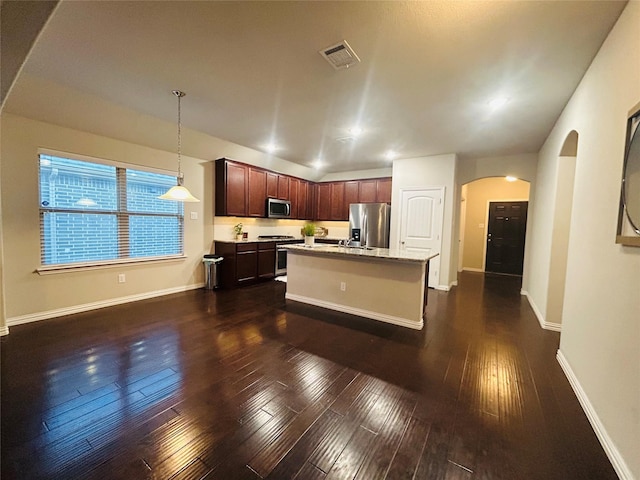 kitchen with pendant lighting, dark hardwood / wood-style flooring, stainless steel appliances, and an island with sink