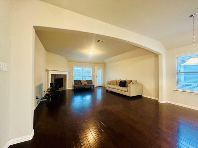 unfurnished living room featuring a healthy amount of sunlight, dark hardwood / wood-style flooring, and lofted ceiling