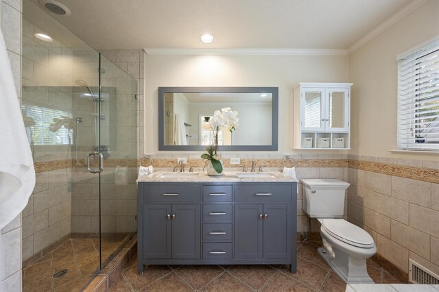 bathroom with tile patterned floors, vanity, a shower with shower door, tile walls, and ornamental molding