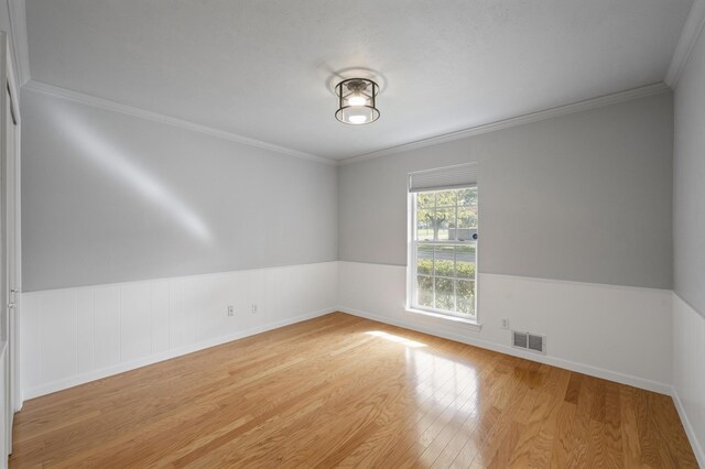 spare room with light wood-type flooring and ornamental molding