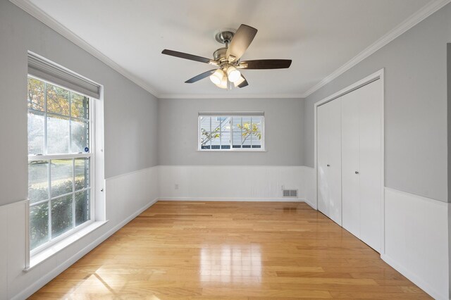 unfurnished bedroom with a closet, light hardwood / wood-style flooring, ceiling fan, and ornamental molding