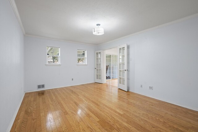 unfurnished room with ornamental molding, french doors, and light hardwood / wood-style flooring