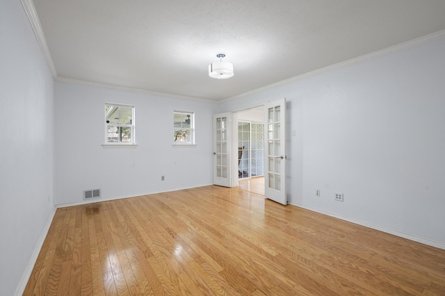 spare room with french doors, ornamental molding, and light wood-type flooring