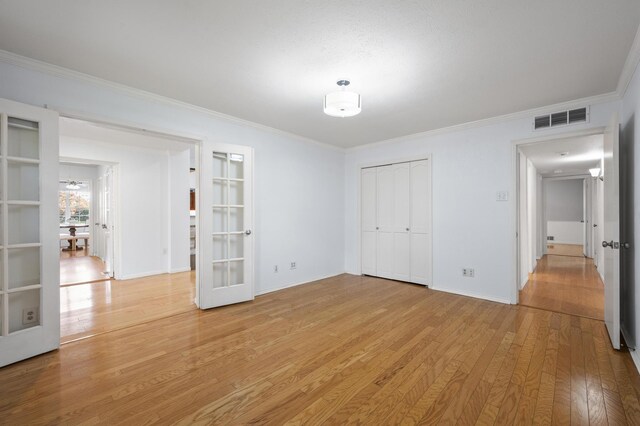 unfurnished bedroom with light hardwood / wood-style floors, crown molding, a closet, and french doors