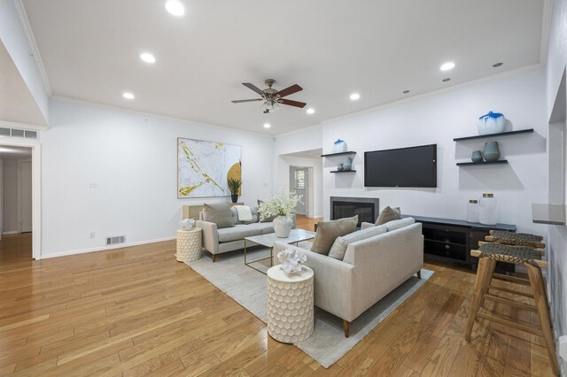 living room featuring light wood-type flooring, ceiling fan, and ornamental molding