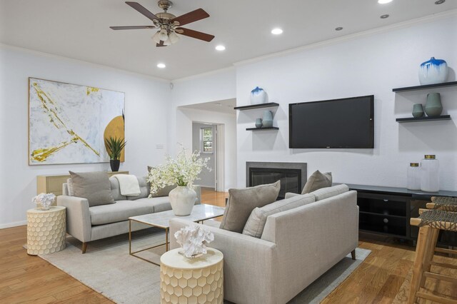 living room with hardwood / wood-style flooring, ceiling fan, and ornamental molding