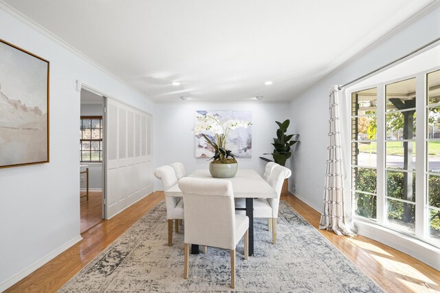 dining area featuring light wood-type flooring, plenty of natural light, and crown molding