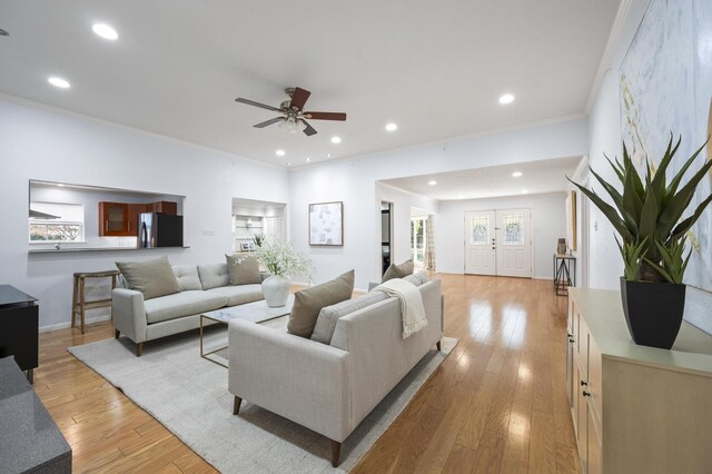 living room featuring ceiling fan, ornamental molding, and light hardwood / wood-style flooring