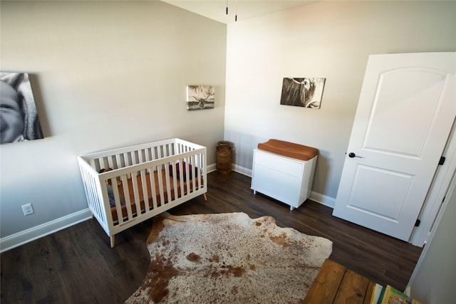 bedroom with dark hardwood / wood-style floors and a nursery area