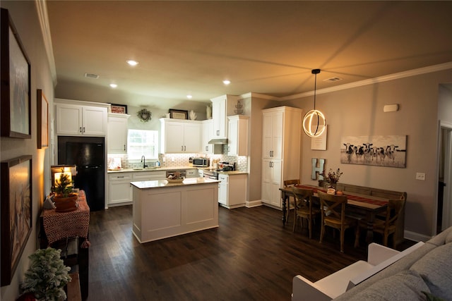 kitchen featuring pendant lighting, sink, stainless steel appliances, a center island, and white cabinets