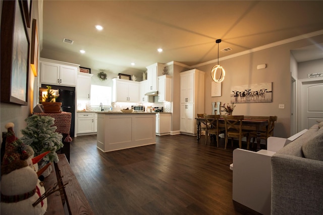 kitchen with dark wood-type flooring, a kitchen island, pendant lighting, decorative backsplash, and white cabinets