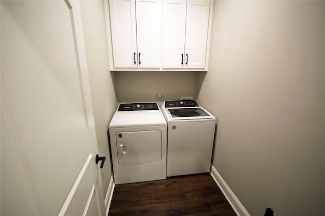 clothes washing area with separate washer and dryer, dark hardwood / wood-style flooring, and cabinets