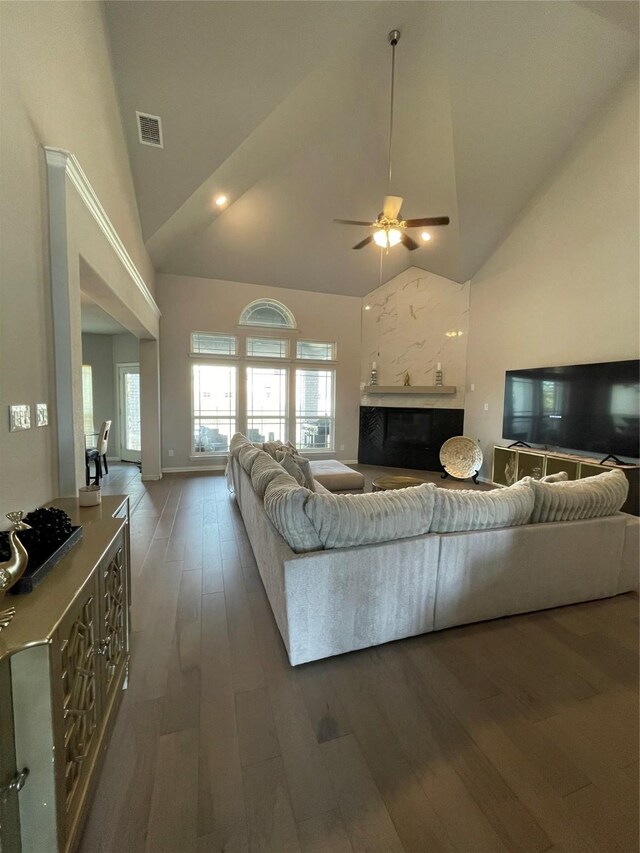 living room featuring a high end fireplace, dark hardwood / wood-style floors, high vaulted ceiling, and ceiling fan