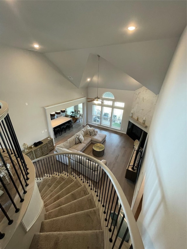 stairs featuring hardwood / wood-style flooring, high vaulted ceiling, and ceiling fan