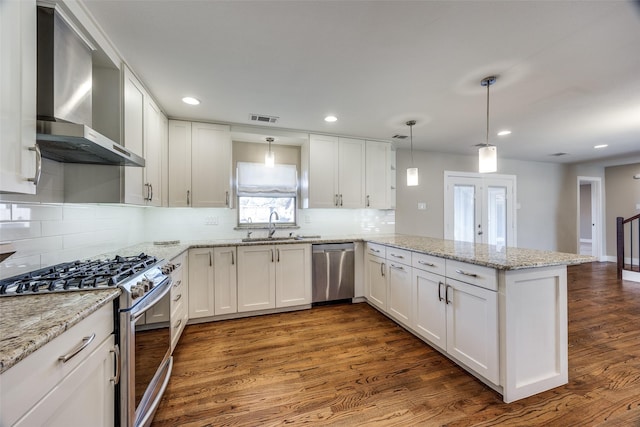 kitchen featuring wall chimney exhaust hood, white cabinetry, stainless steel appliances, and kitchen peninsula