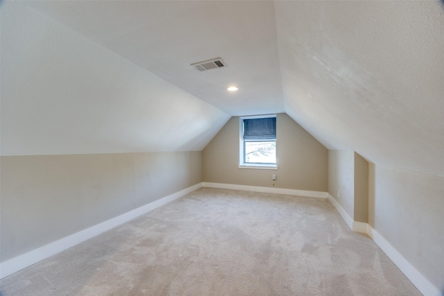 additional living space featuring light carpet, a textured ceiling, and lofted ceiling