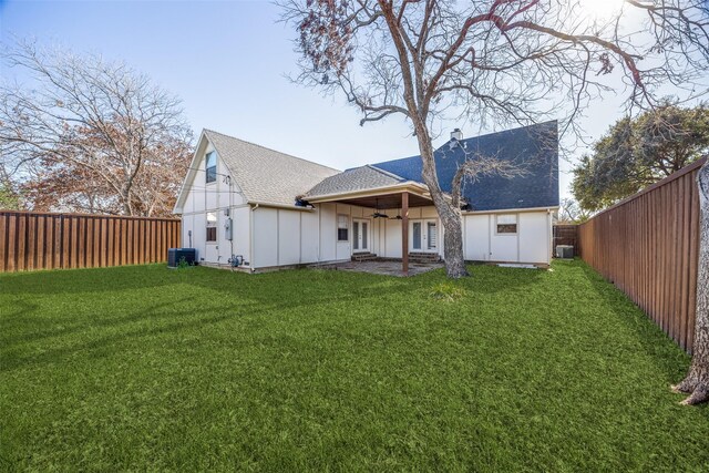 back of property with ceiling fan, central air condition unit, and a yard