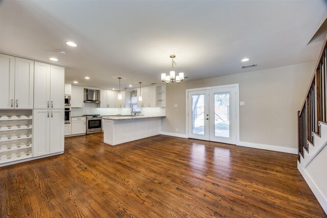 kitchen featuring kitchen peninsula, dark hardwood / wood-style flooring, stainless steel appliances, wall chimney range hood, and white cabinets