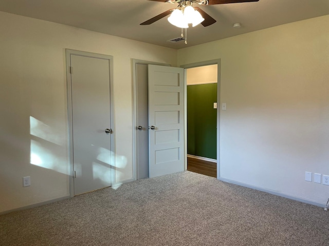 unfurnished bedroom with ceiling fan and dark carpet