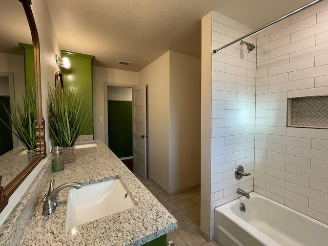 bathroom with vanity, tiled shower / bath combo, tile patterned flooring, and a textured ceiling