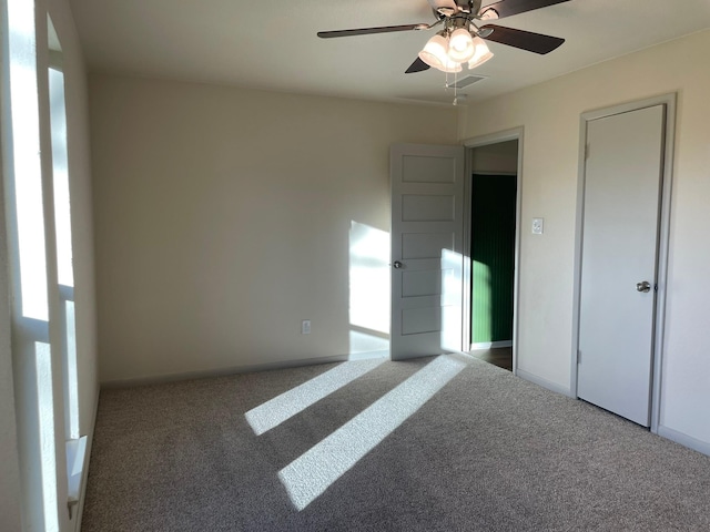 unfurnished bedroom with dark colored carpet and ceiling fan