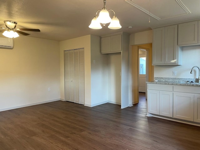 kitchen with decorative light fixtures, sink, a wall mounted AC, dark hardwood / wood-style flooring, and light stone countertops