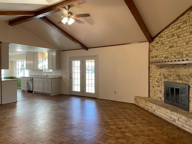 unfurnished living room with dark parquet flooring, a brick fireplace, ceiling fan, sink, and vaulted ceiling with beams