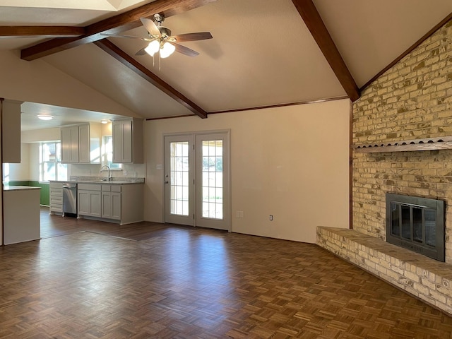 unfurnished living room with a healthy amount of sunlight, dark parquet flooring, a fireplace, and sink