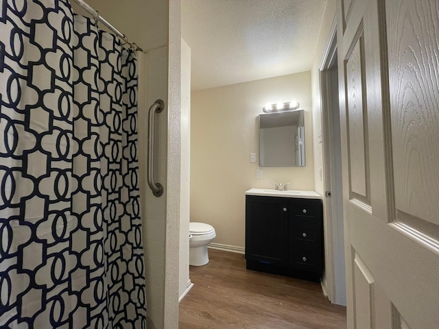 bathroom featuring toilet, a shower with curtain, wood-type flooring, a textured ceiling, and vanity