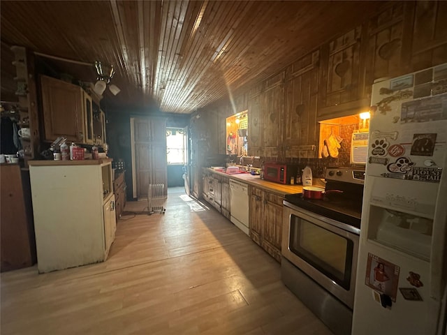 kitchen featuring ceiling fan, sink, wood walls, white appliances, and light wood-type flooring