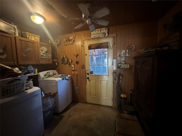 clothes washing area with ceiling fan, cabinets, dark colored carpet, independent washer and dryer, and wood walls