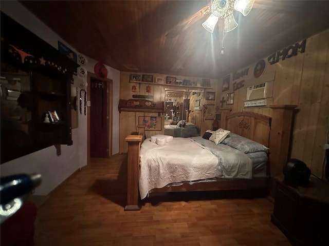 bedroom with hardwood / wood-style floors, ceiling fan, and wooden walls