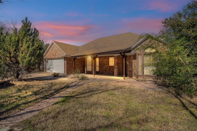 ranch-style house featuring a garage, a yard, concrete driveway, and brick siding