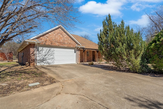 view of side of property with a garage, concrete driveway, and brick siding