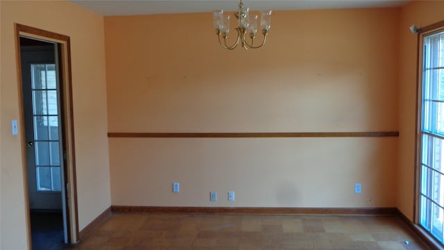 unfurnished room with a chandelier